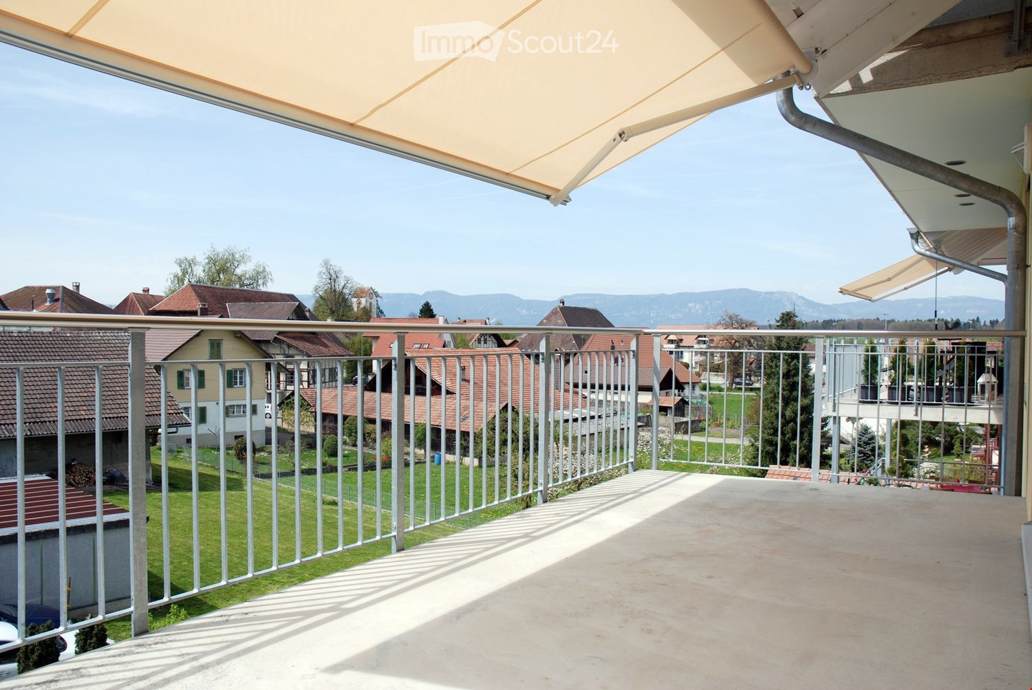 Balcony with metal railings, retractable awning, view of the town and mountains