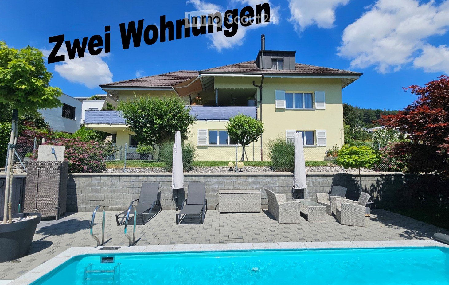 Yellow house, brick wall, blue pool, patio with lounge chairs and tables, fence, trees and plants