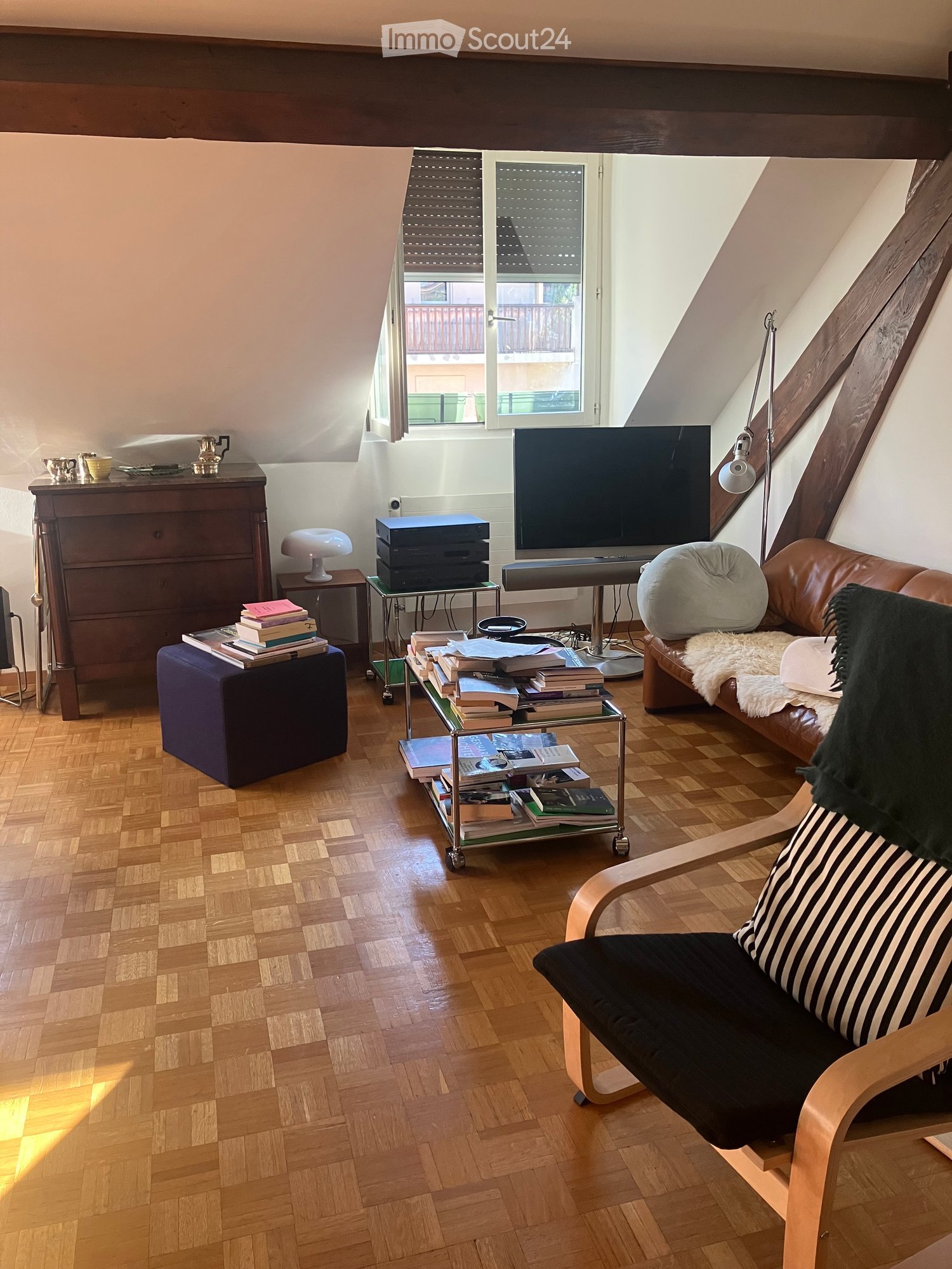 wooden floor, wooden beams, wooden furniture, TV, books, lamp, couch, chair, ottoman