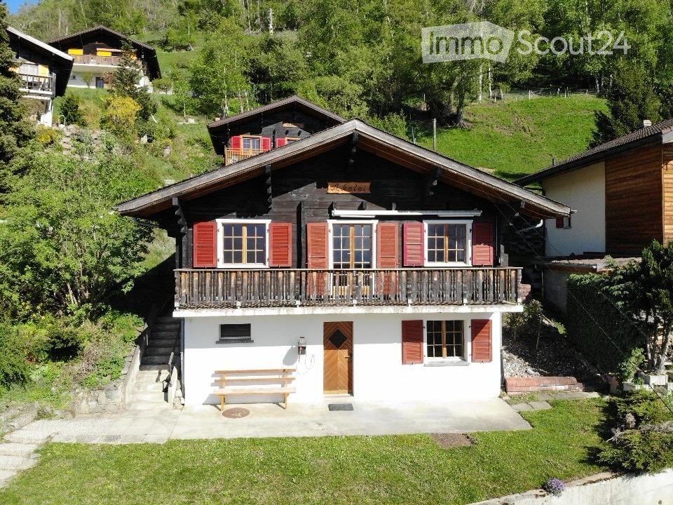 wooden house, red shutters, wooden balcony, wooden bench, wooden door, surrounded by trees and grass