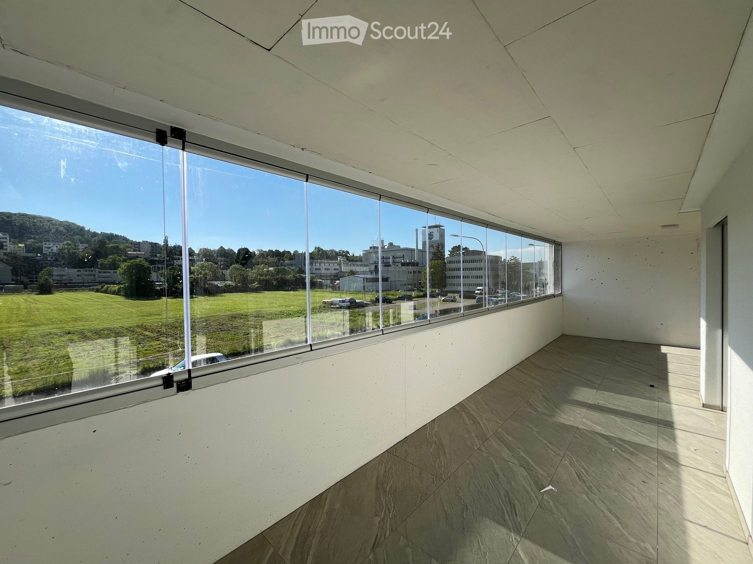large windows, tiled floor, view of a grassy field and buildings