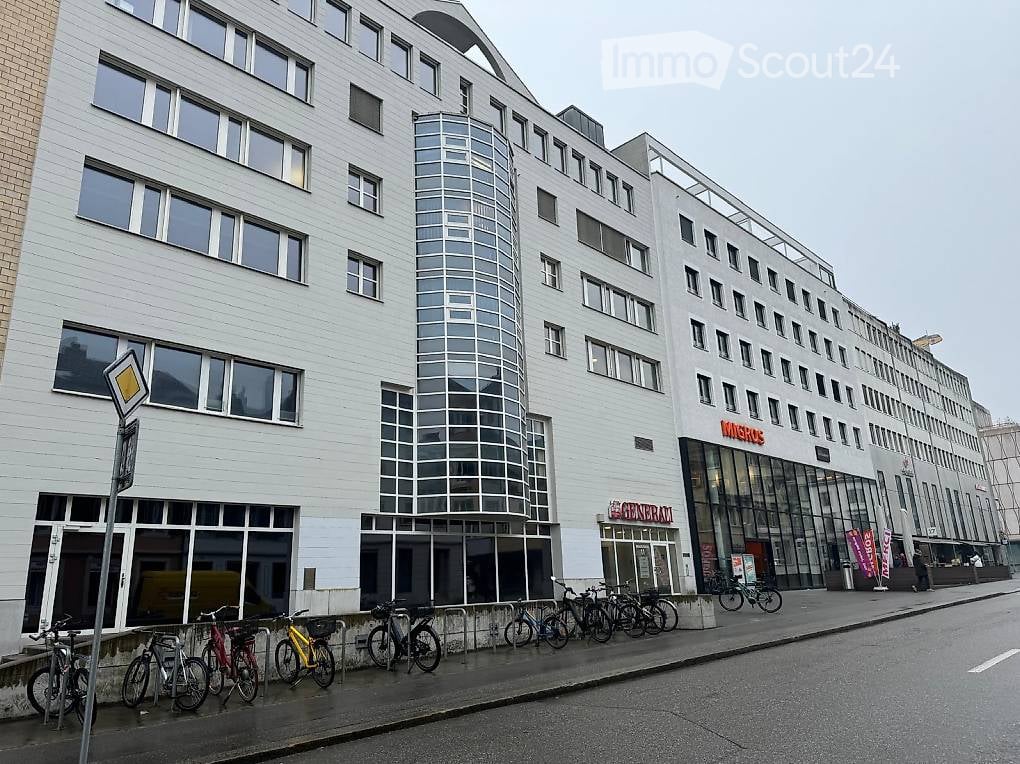 Modern office building with glass facade, multiple floors, bicycles parked outside