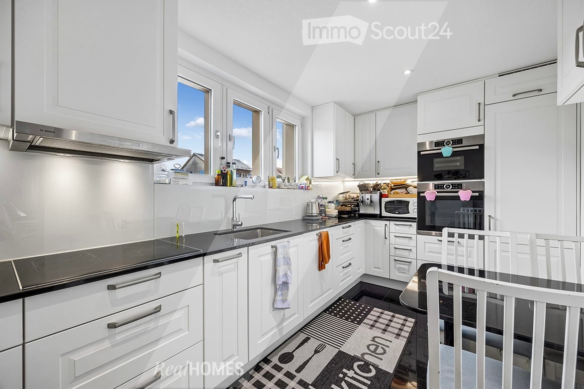 modern kitchen, white cabinets, black countertops, stainless steel appliances, large windows