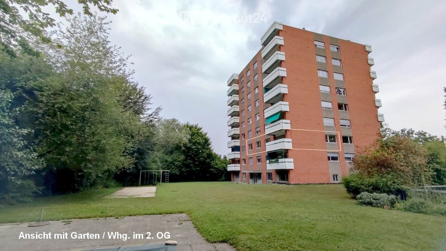 A multi-story building with brick facade, balconies, and a green lawn in front.
