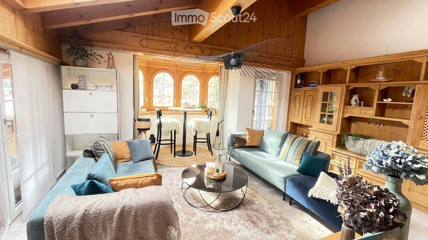 Living room with wooden ceiling, two sofas, coffee table, and decorative items.