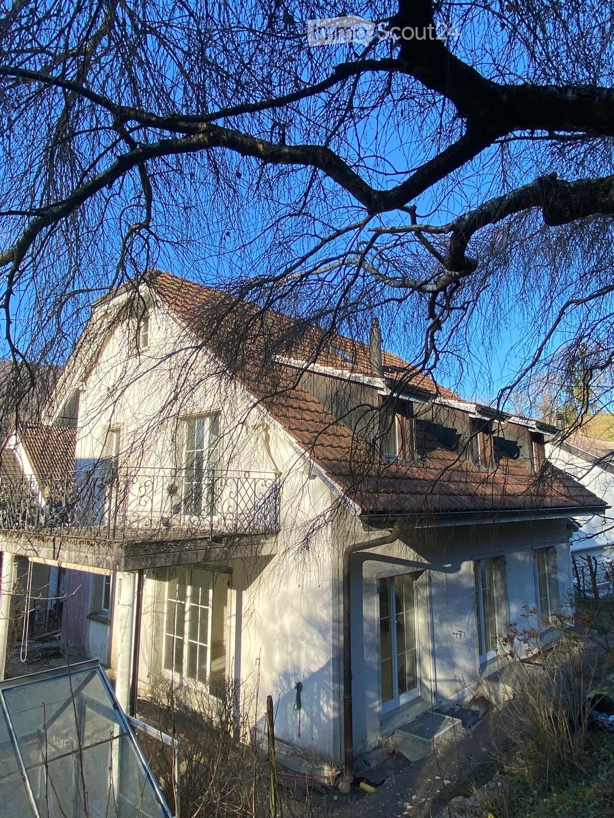 white house, brown roof, balcony, glass windows, glass door, chimney, small greenhouse