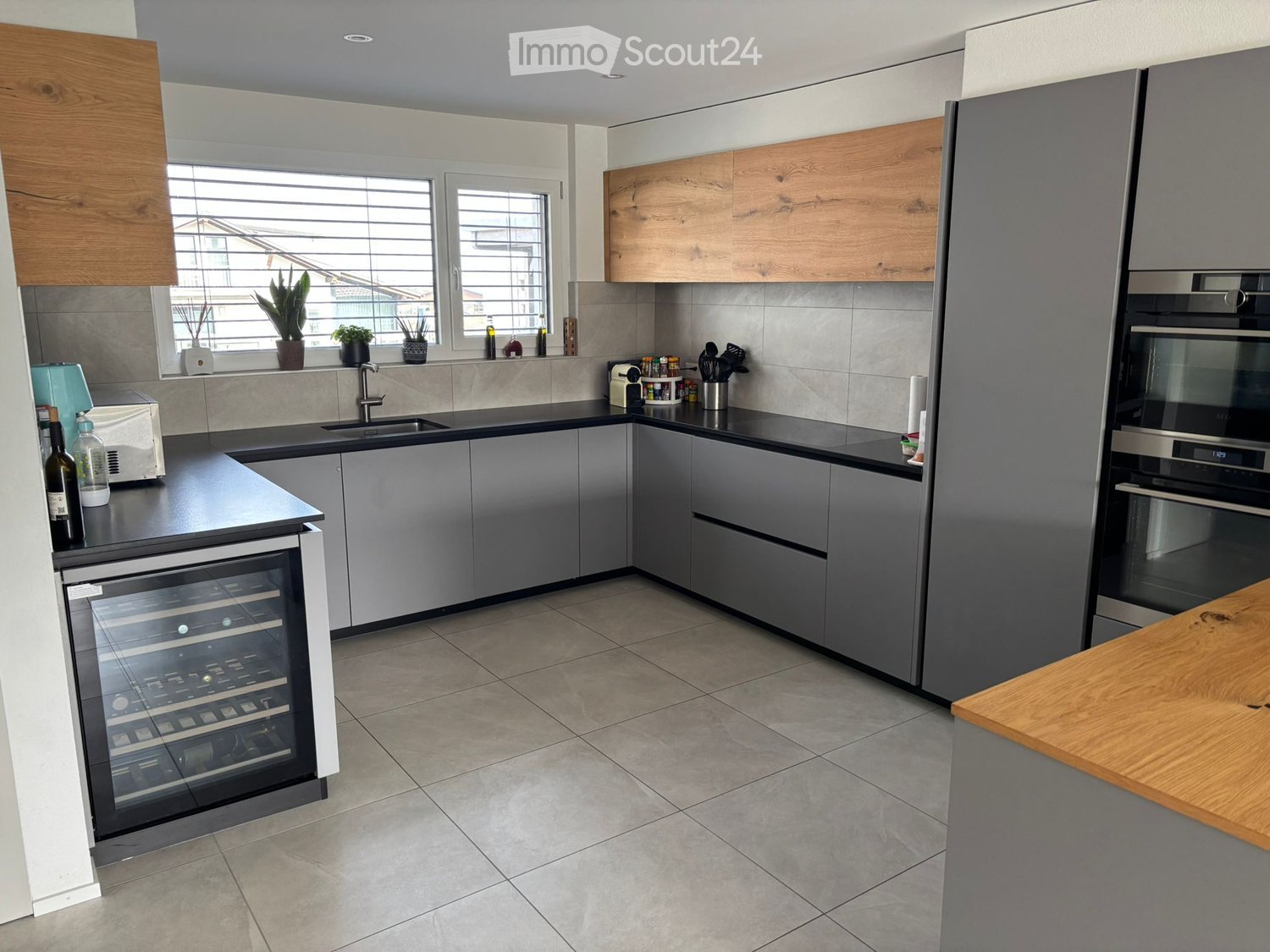 modern kitchen with wooden cabinets, tiled floor, two ovens, wine cooler, double sink, island, window