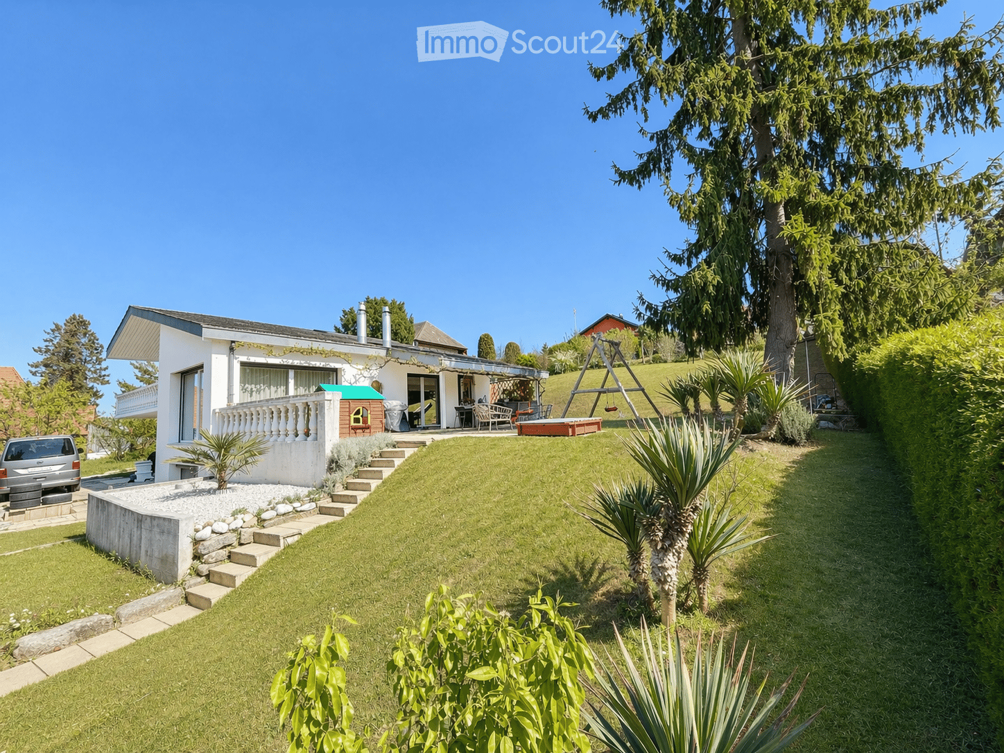 Detached house, white exterior, large garden, swing, car parked, steps leading to entrance