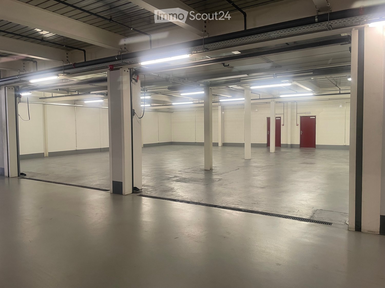 Unfurnished Room. Empty warehouse with concrete floor, white walls, and metal beams. There are no visible objects or furniture.