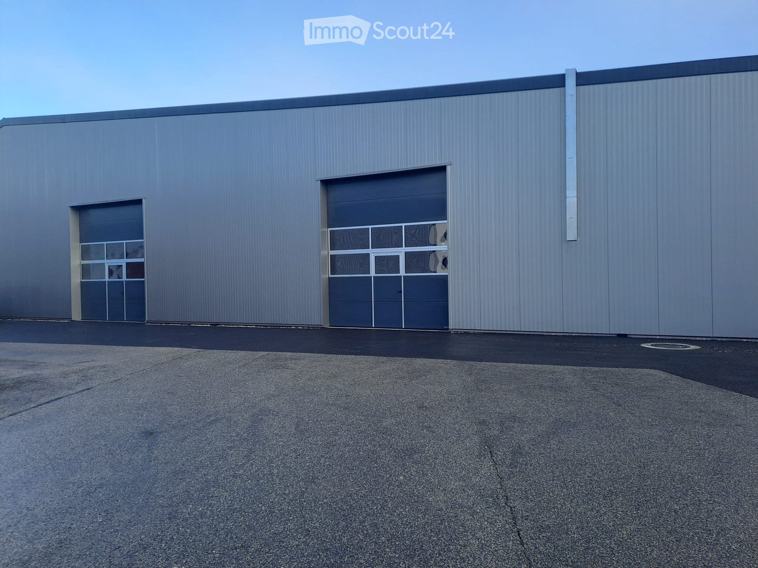 Modern industrial building with large garage doors and a smooth metal facade.