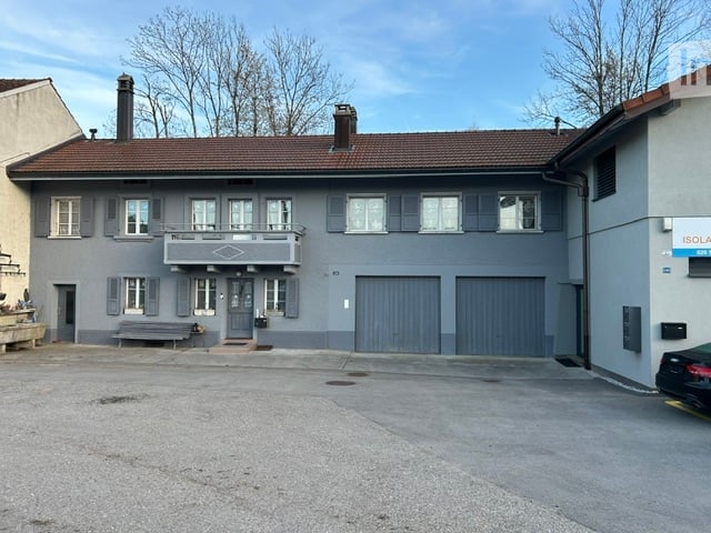 2 story house, gray exterior, brown roof, 2 garages, balcony, bench in front