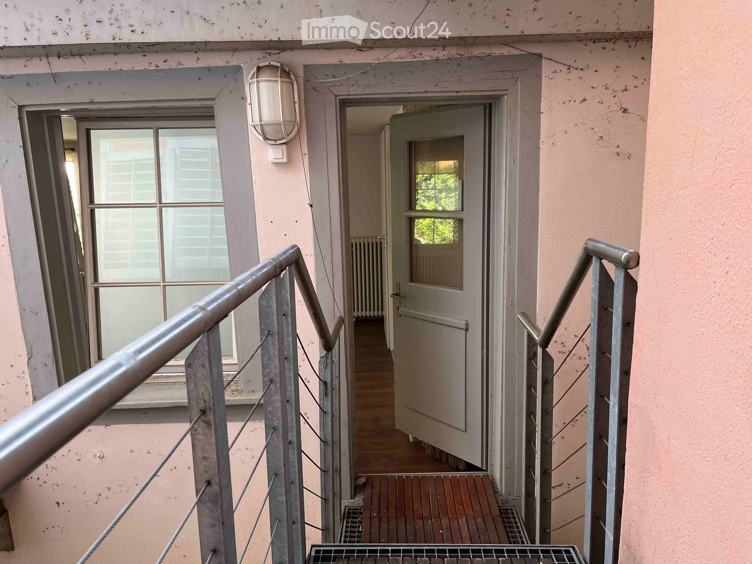 Raised staircase with wooden steps, metal handrails, open door, street lamp, wooden floor