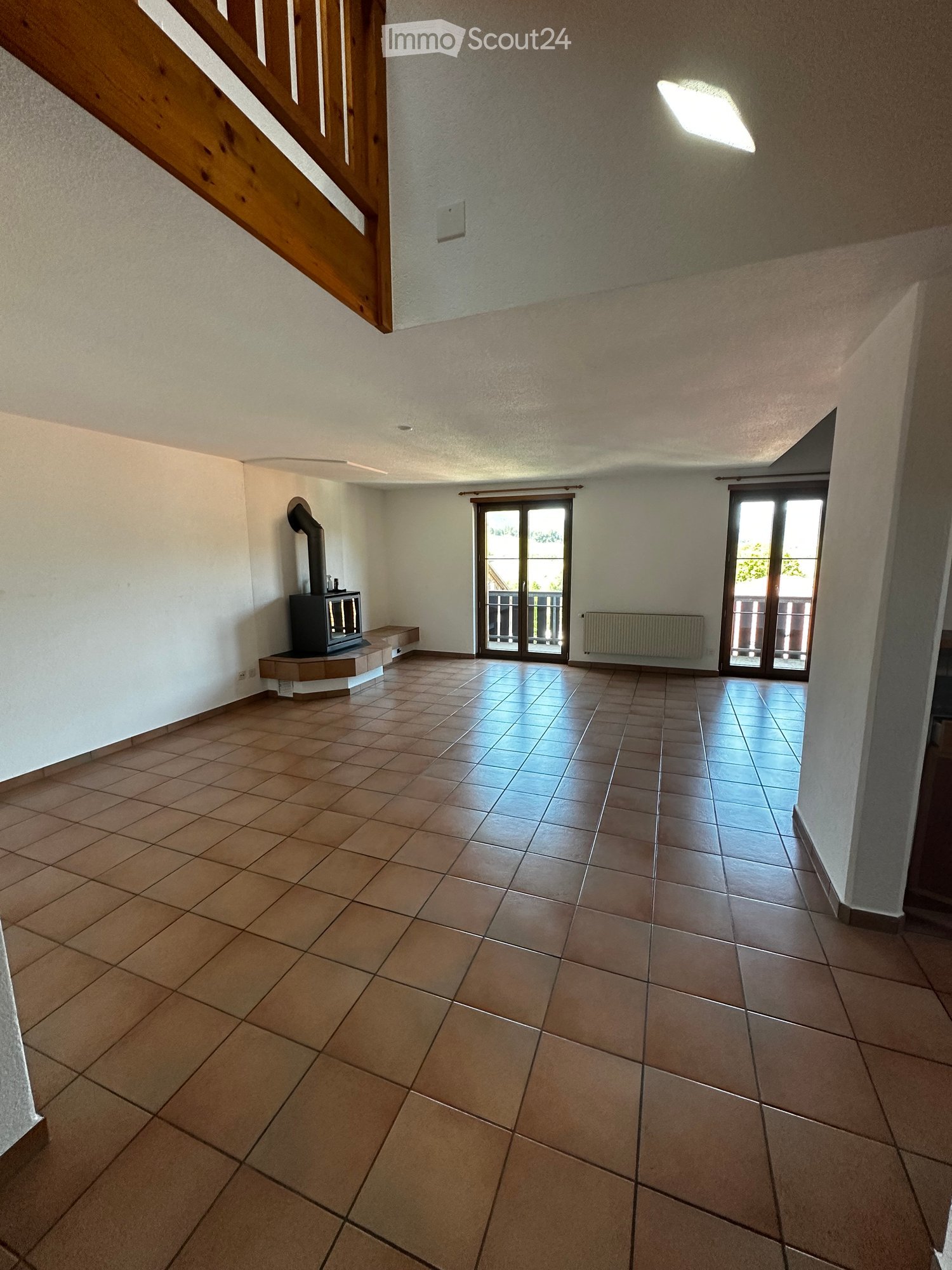 empty room with fireplace, balcony, white walls, wooden flooring