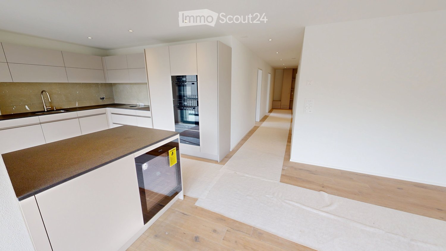 Kitchen. Modern kitchen with white cabinets, a dark countertop, and integrated appliances including a sink, oven, and microwave. The floor is light wood, and the space is open and bright.
