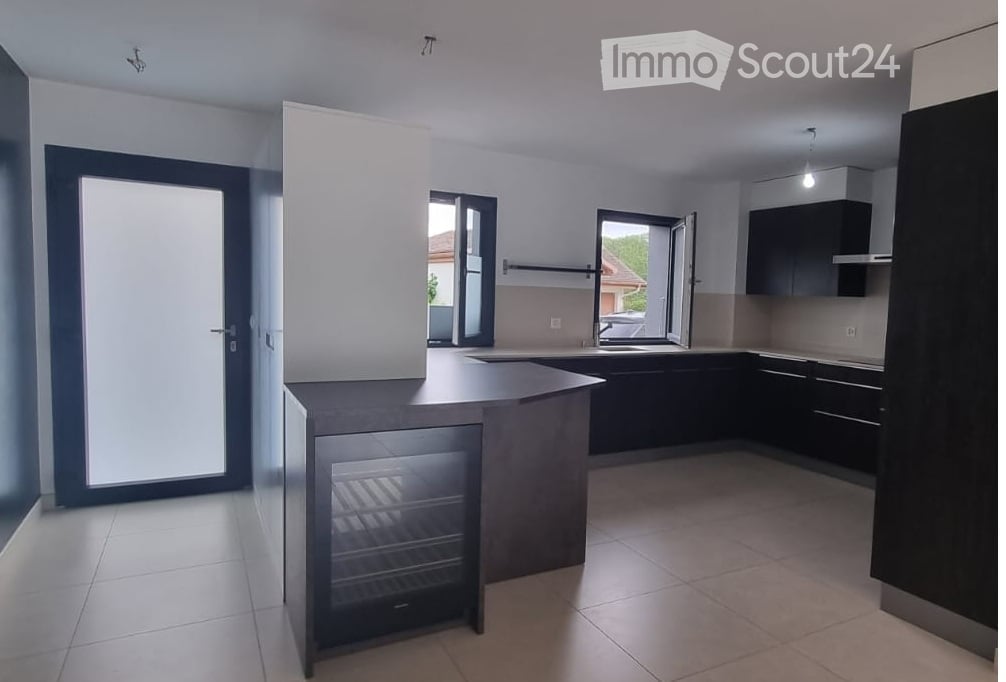 Modern kitchen with dark cabinets, a central island, and a built-in refrigerator. The space features large windows and a sleek, contemporary design.
