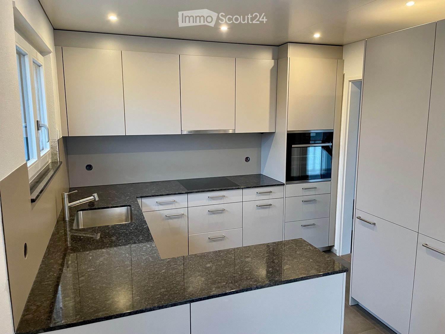 modern kitchen, white cabinets, granite countertops, stainless steel sink, built-in oven, dishwasher, granite backsplash