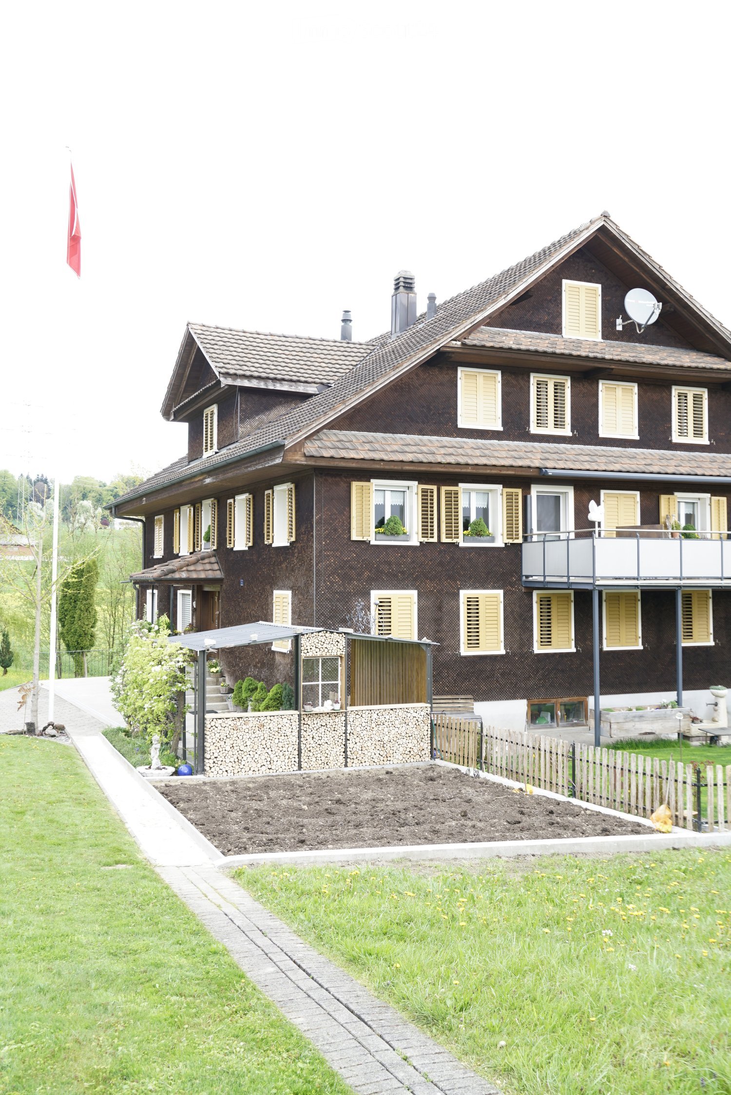 3 story house, brown exterior, yellow shutters, balcony, garden, satellite dish