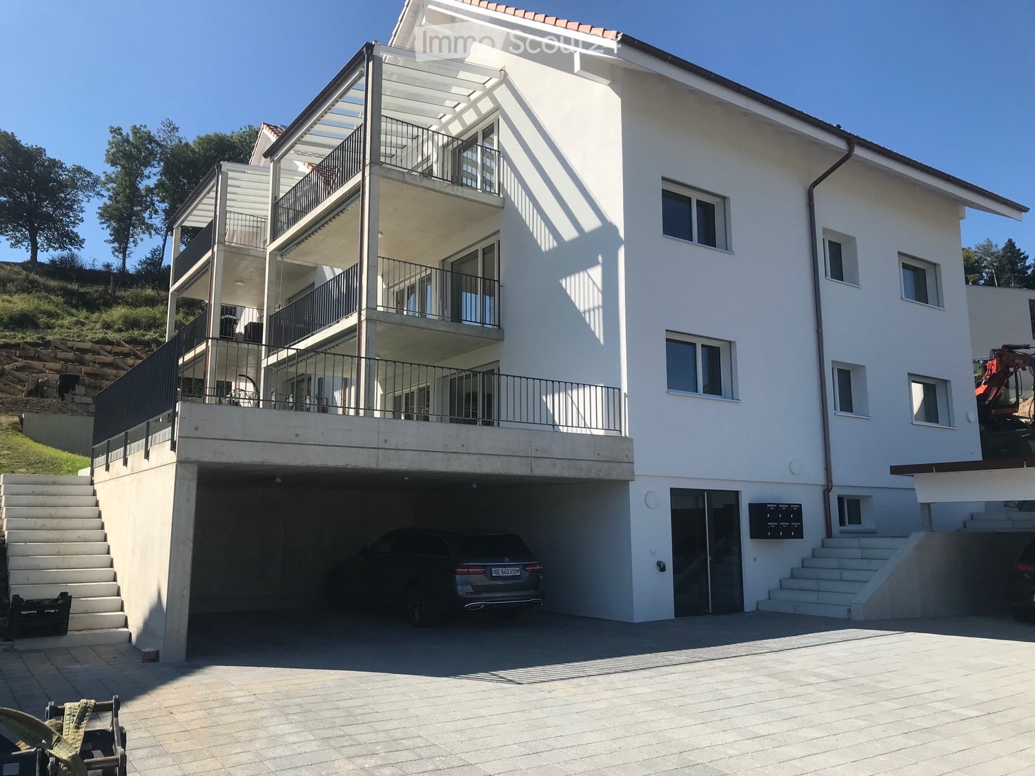Modern apartment building, white exterior, garage, balconies, staircases