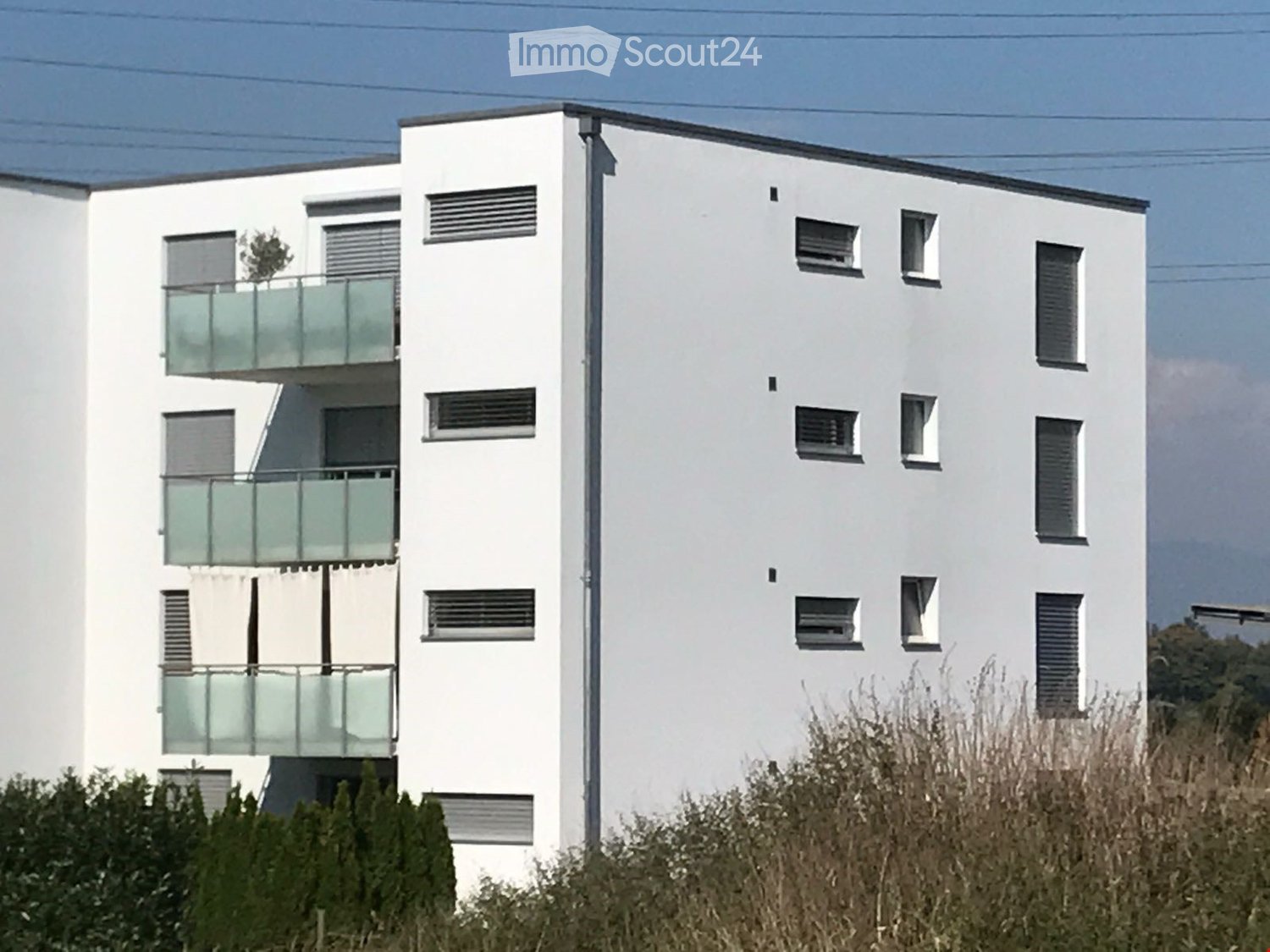 white exterior, glass balcony railings, multiple windows, 5 stories