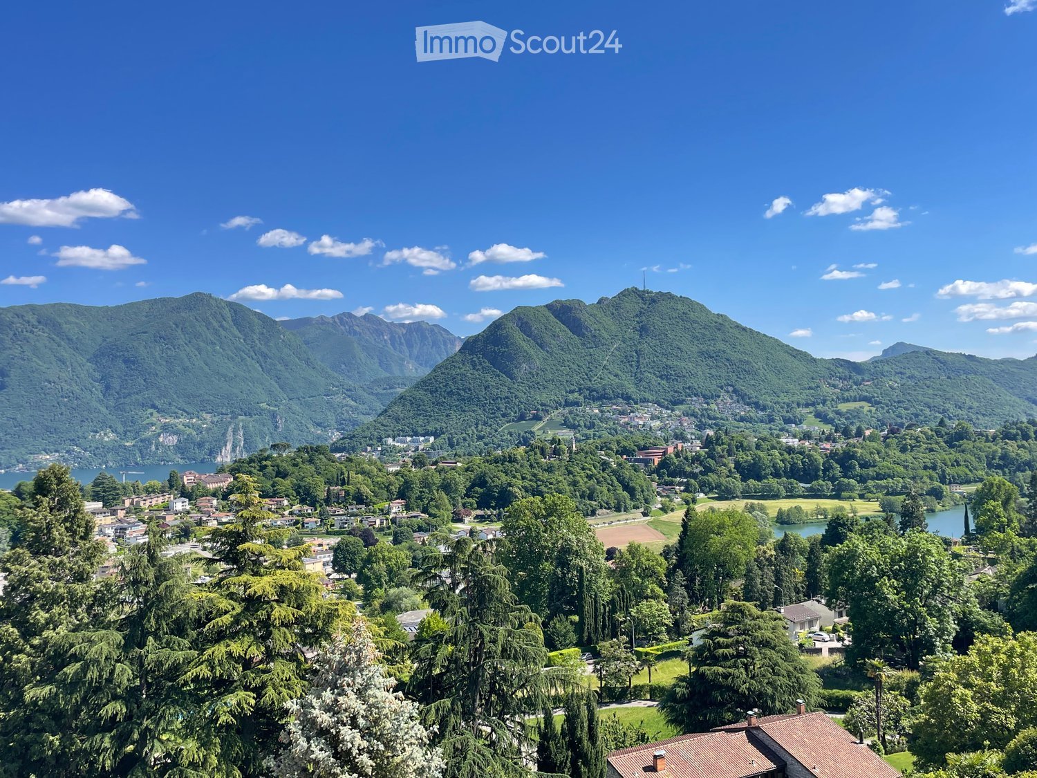 Garden / Outdoor Area. Panoramic view of a town nestled in a valley surrounded by lush green hills and mountains, with a lake visible in the distance.
