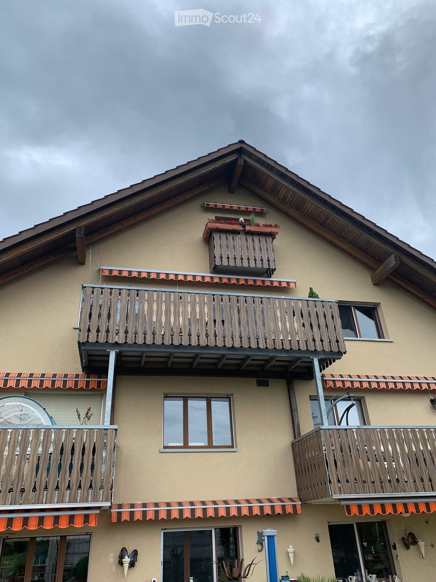 Building. Two-story house with multiple balconies, wooden railings, and decorative flower boxes on the roof.