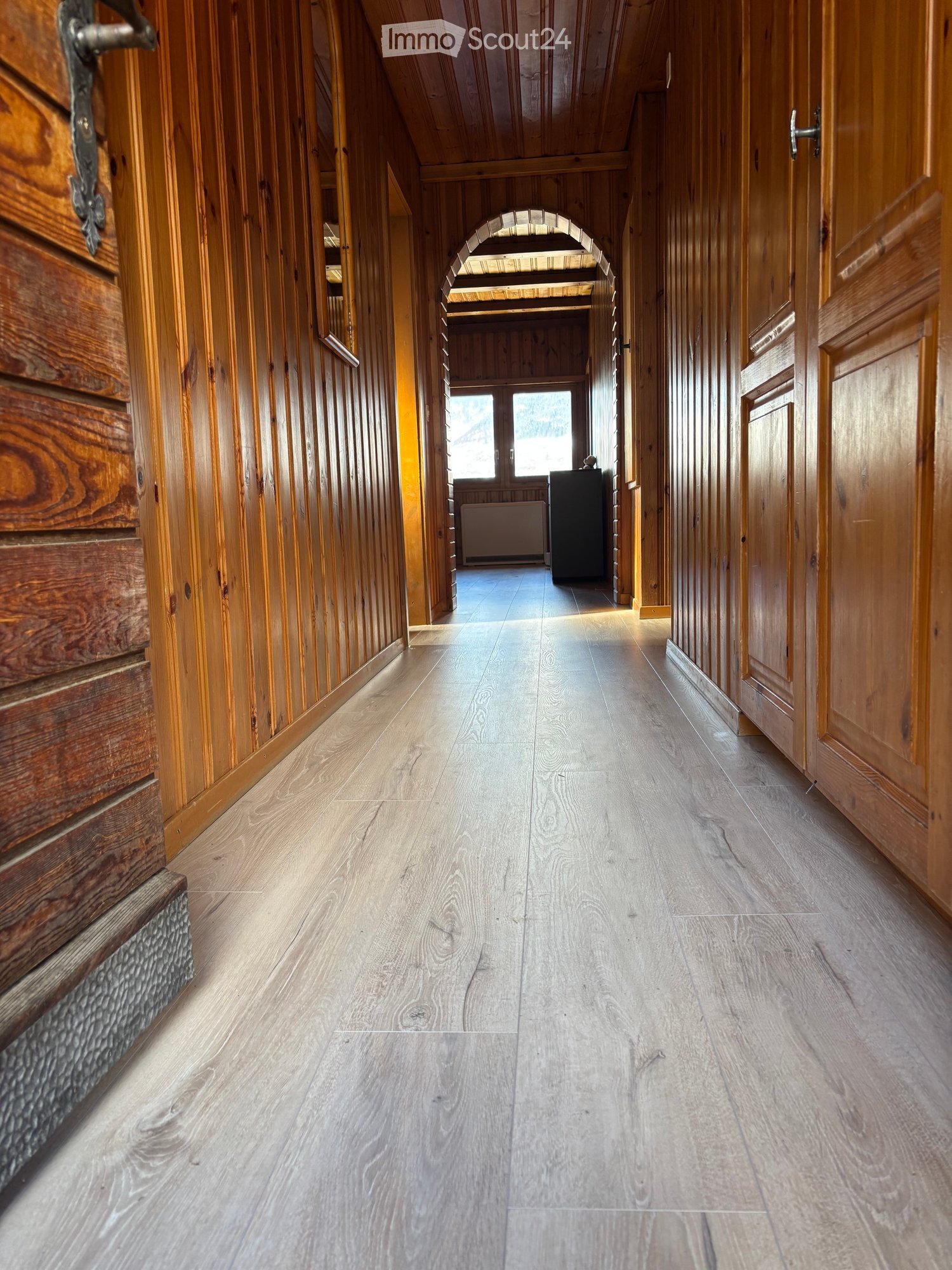 Corridor / Hallway. Wooden-paneled hallway with light-colored wooden flooring, arched ceiling, and doors on both sides.