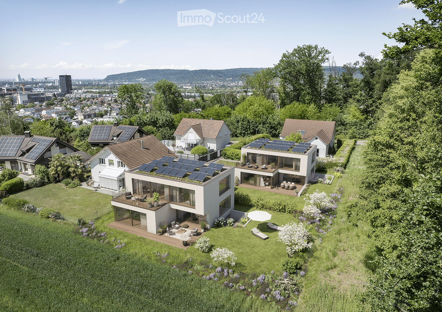 House. Aerial view of a modern residential complex with multiple houses, solar panels on roofs, spacious gardens, and outdoor seating areas.