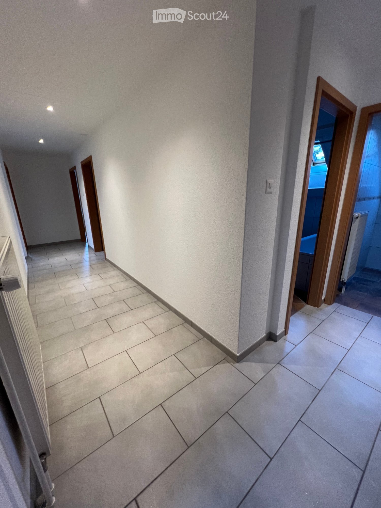 Tiled floor, white walls, three doors, radiators