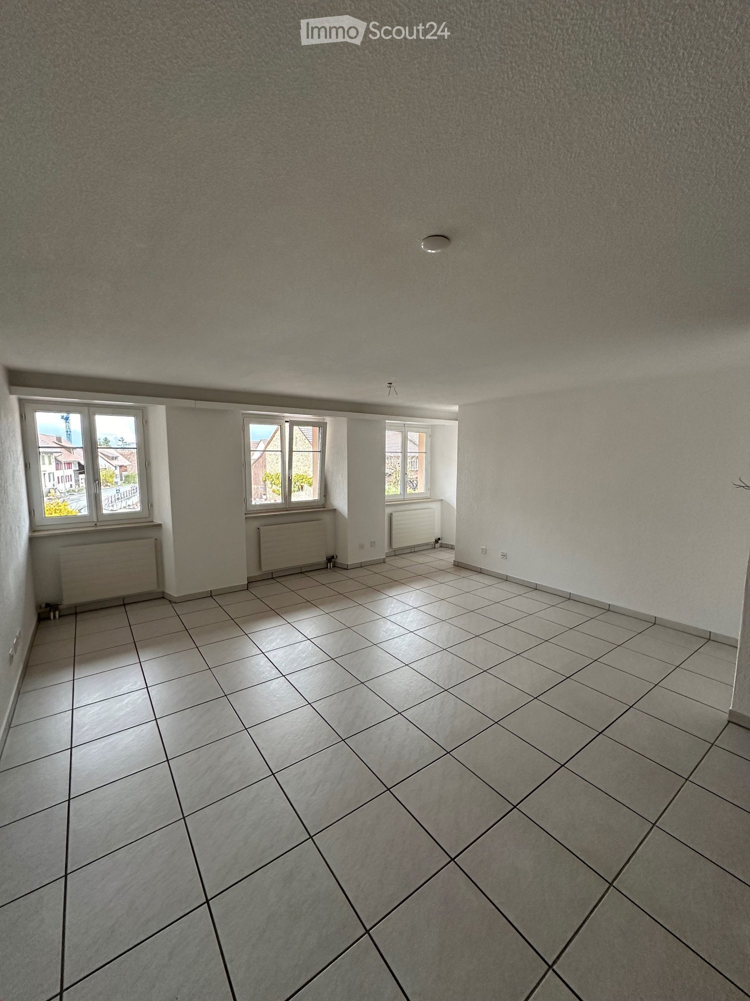 Unfurnished Room. Empty room with tiled floor, white walls, and three windows with radiators underneath. No furniture or equipment present.