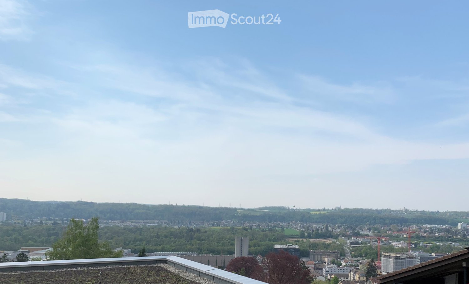 Balcony / Terrace. Panoramic cityscape view from a rooftop terrace, featuring a mix of residential and commercial buildings, green spaces, and distant hills under a partly cloudy sky.