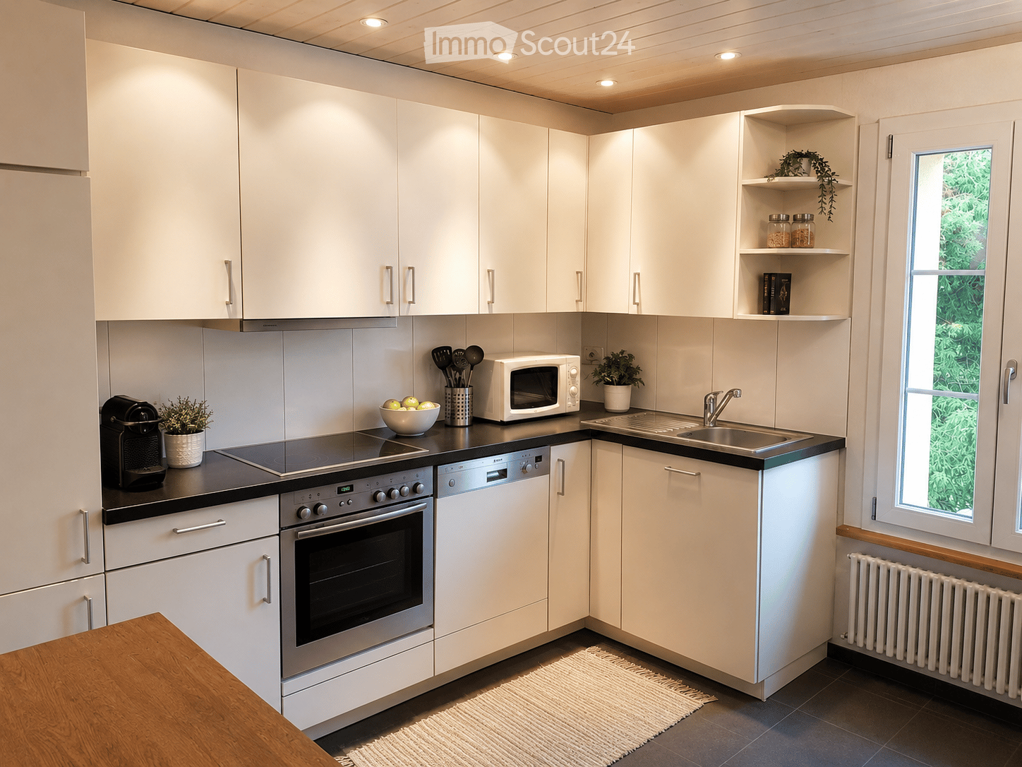 Kitchen. Modern kitchen with white cabinets, stainless steel appliances, and a black countertop. Includes an oven, dishwasher, microwave, coffee maker, and a small table.