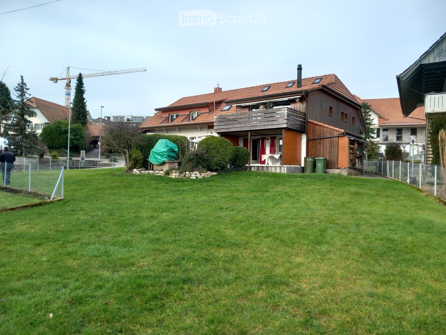 2 story house, red roof, brown siding, wooden balcony, fenced front yard