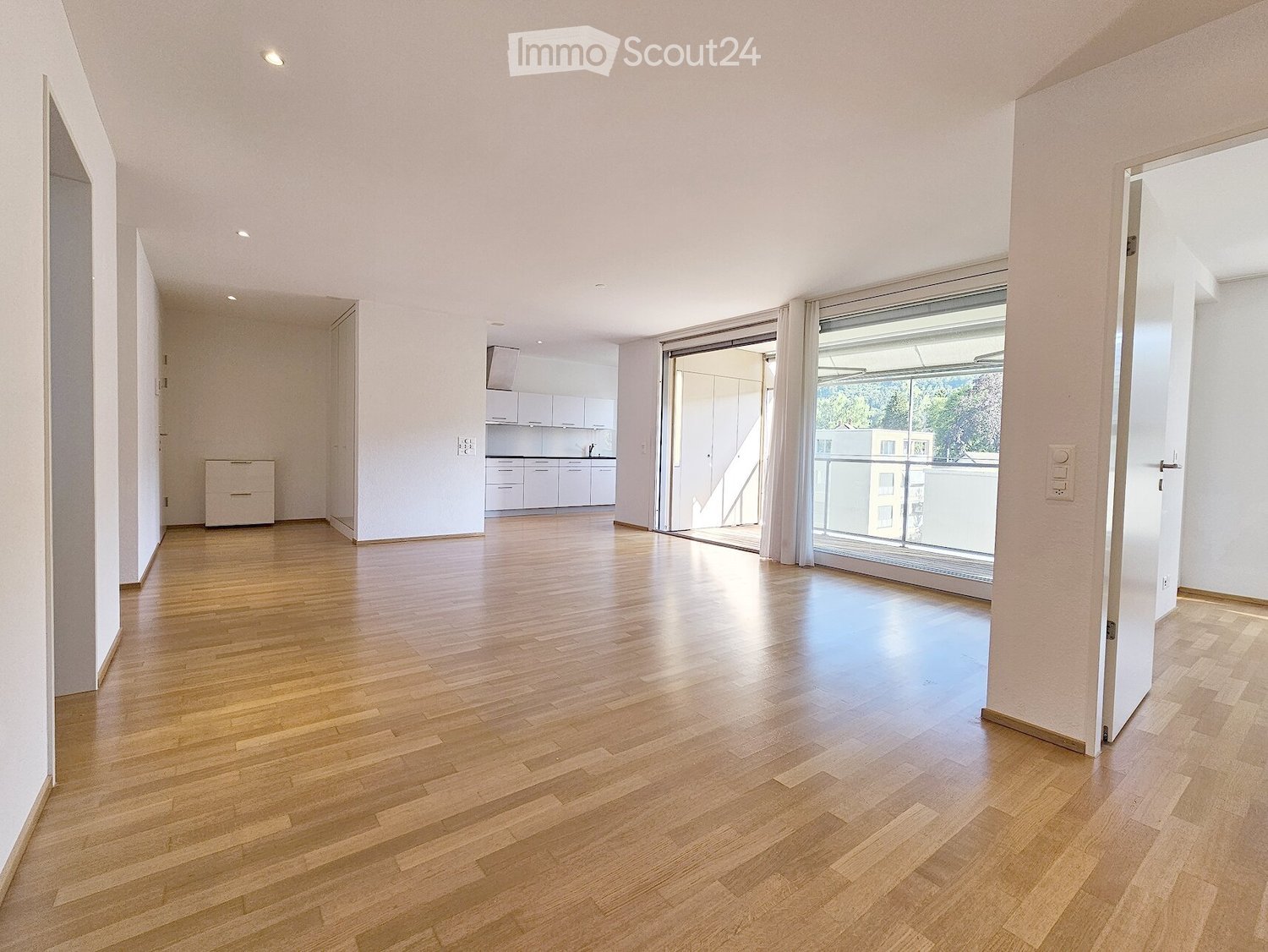 Unfurnished Room. Bright, unfurnished living space with wooden flooring, large windows, and a sliding glass door leading to a balcony.