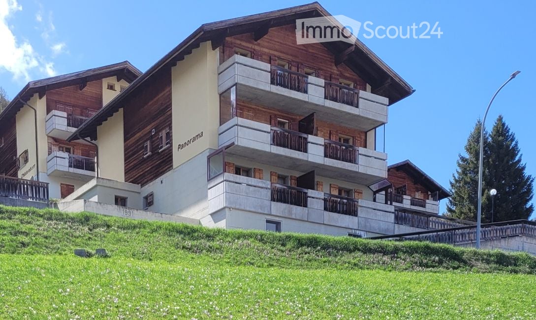 Building. Multi-story wooden building with balconies and a grassy slope in front.