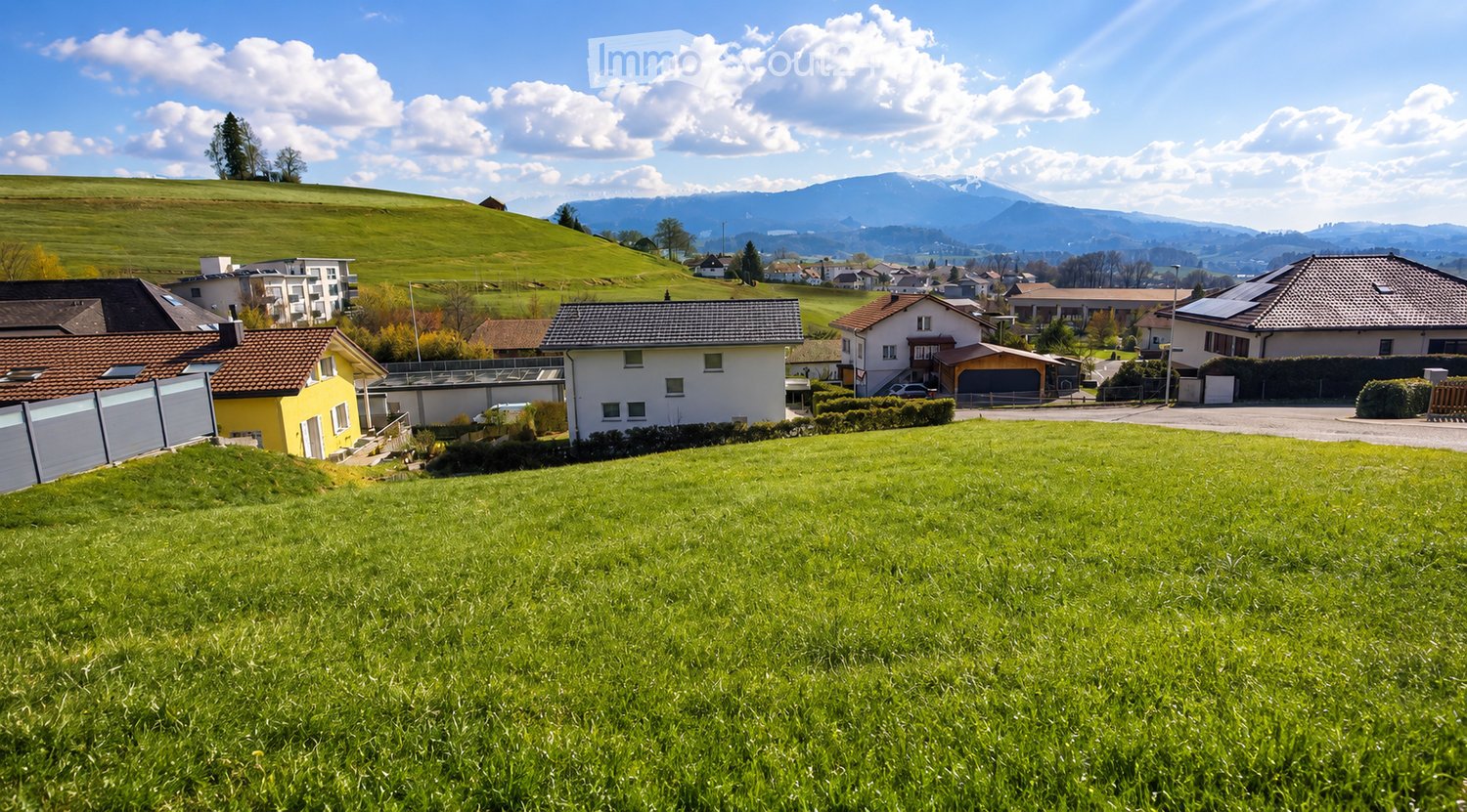 Building. Residential area with multiple houses, surrounded by green hills and mountains under a partly cloudy sky.
