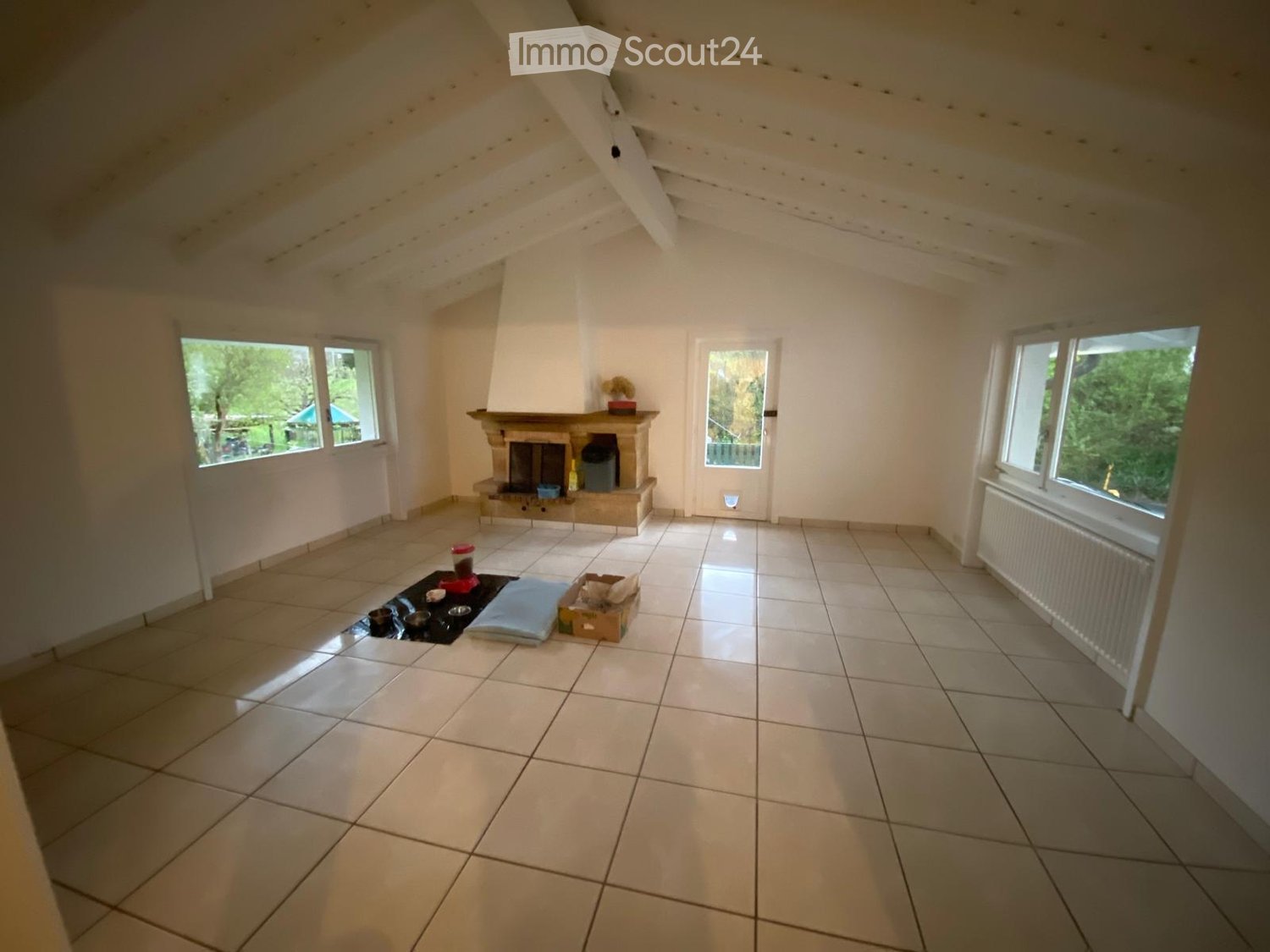 Unfurnished Room. Empty room with tiled floor, white walls, large windows, and a fireplace with a small decorative item on the mantel.