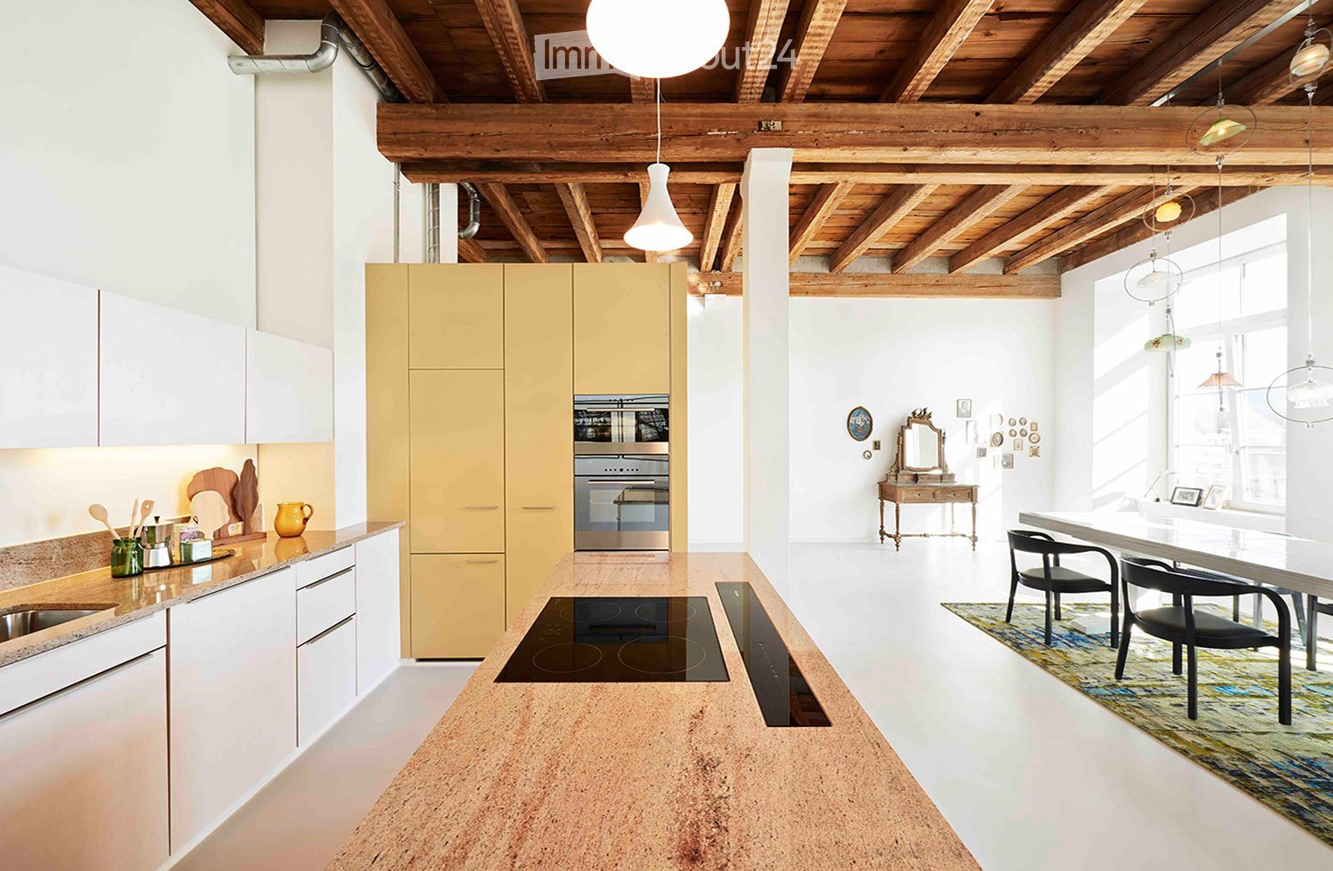 Furnished Room. Open-plan kitchen and dining area with white and beige cabinets, an induction cooktop, a built-in oven, and a large island countertop. The space features modern pendant lights, a dining table with chairs, and a small vanity with a mirror.
