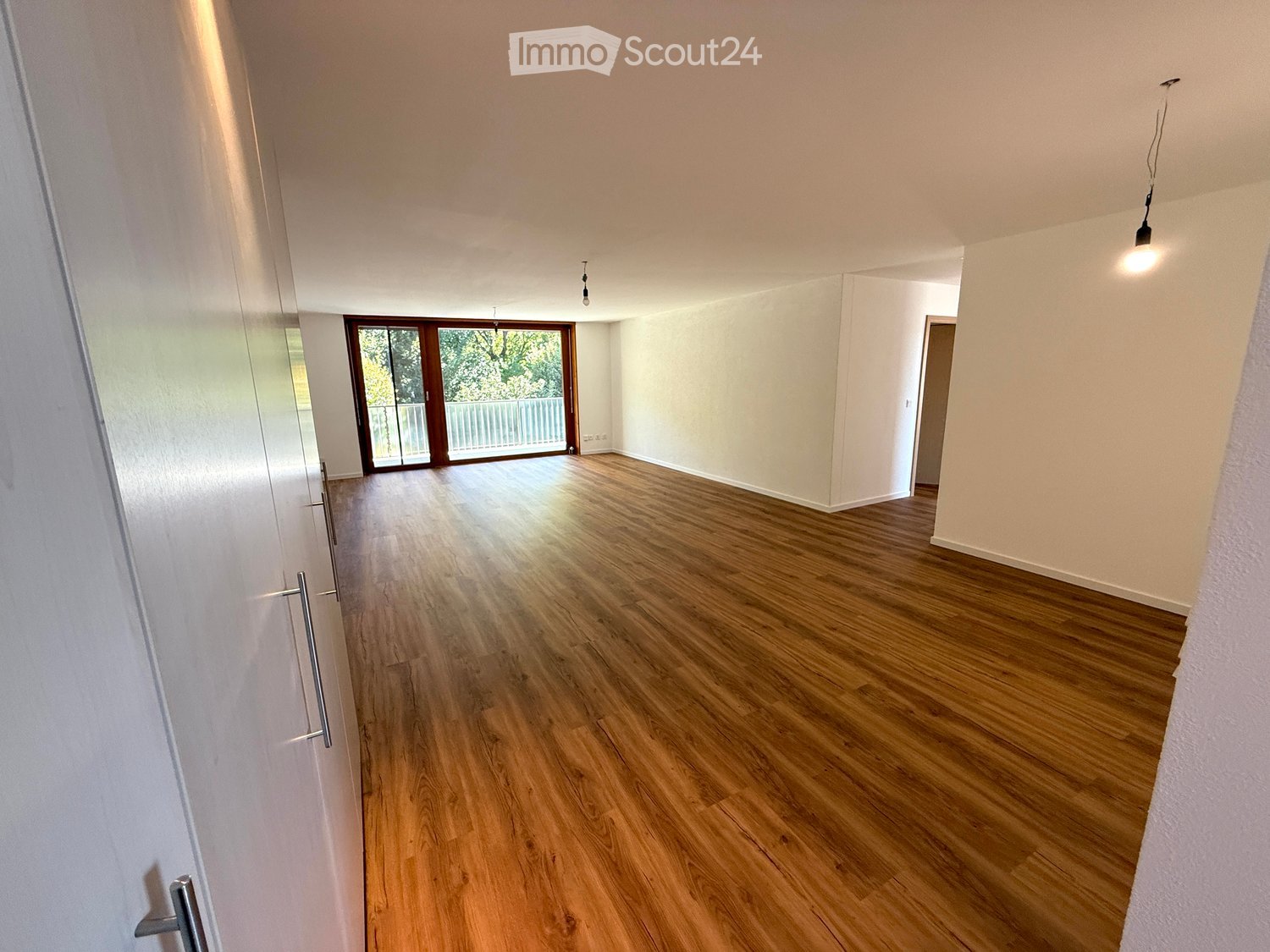 large windows, wooden floor, sliding glass door, balcony, white walls, bright lighting