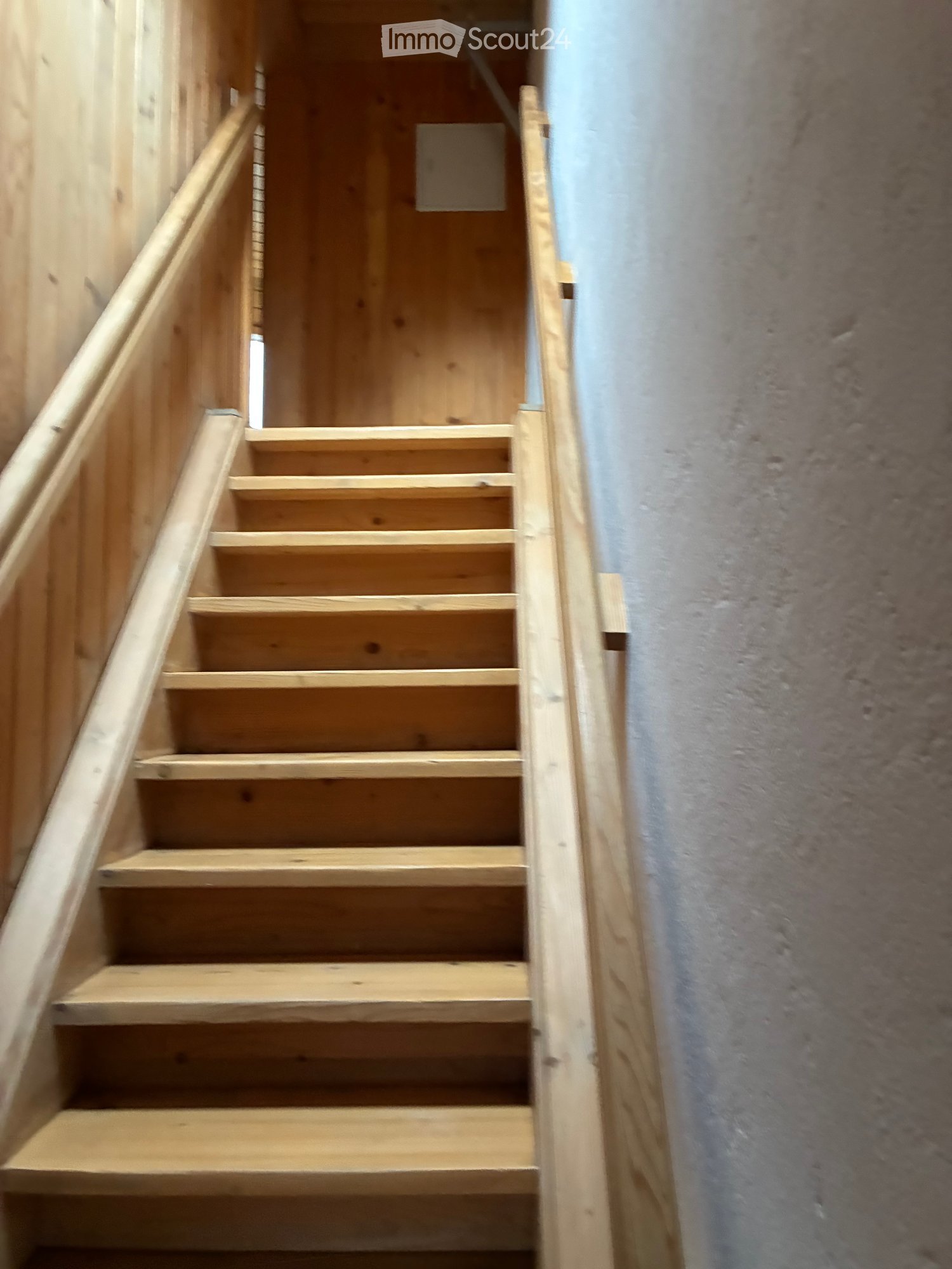 Corridor / Hallway. Wooden staircase with handrails and a grey wall in the background.