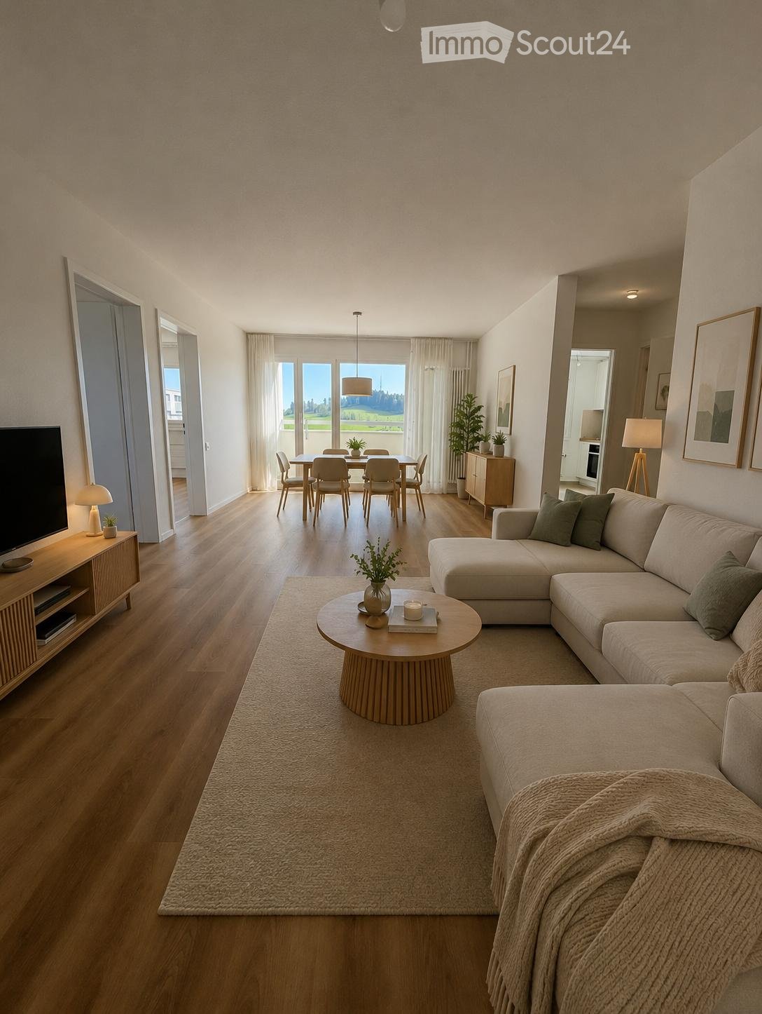 Modern living and dining area with a sectional sofa, coffee table, dining table with chairs, and a TV stand. The space features wooden flooring, large windows with sheer curtains, and decorative plants.