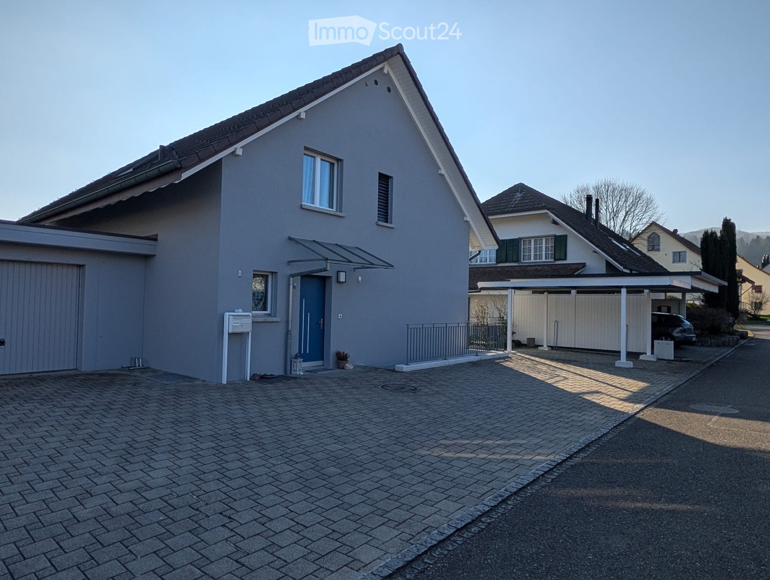 Detached house with garage, brick walls, grey roof, double windows, and a paved driveway
