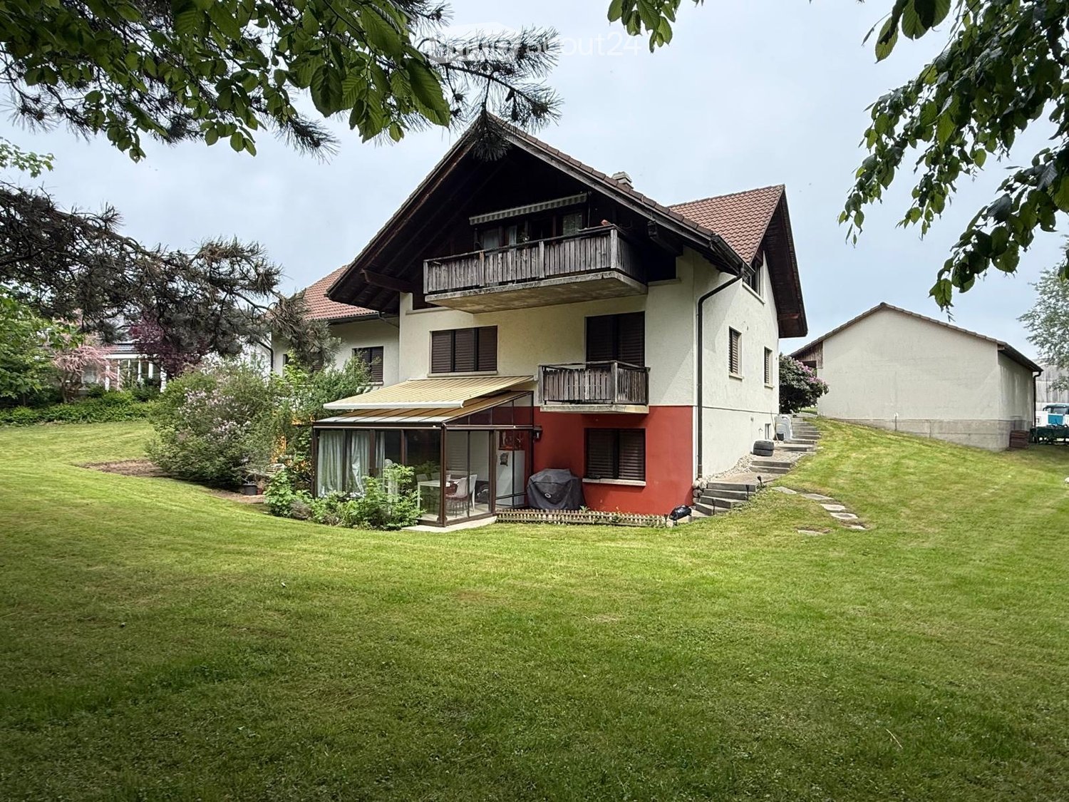 House. Two-story house with a red and white exterior, multiple balconies, and a well-maintained lawn.