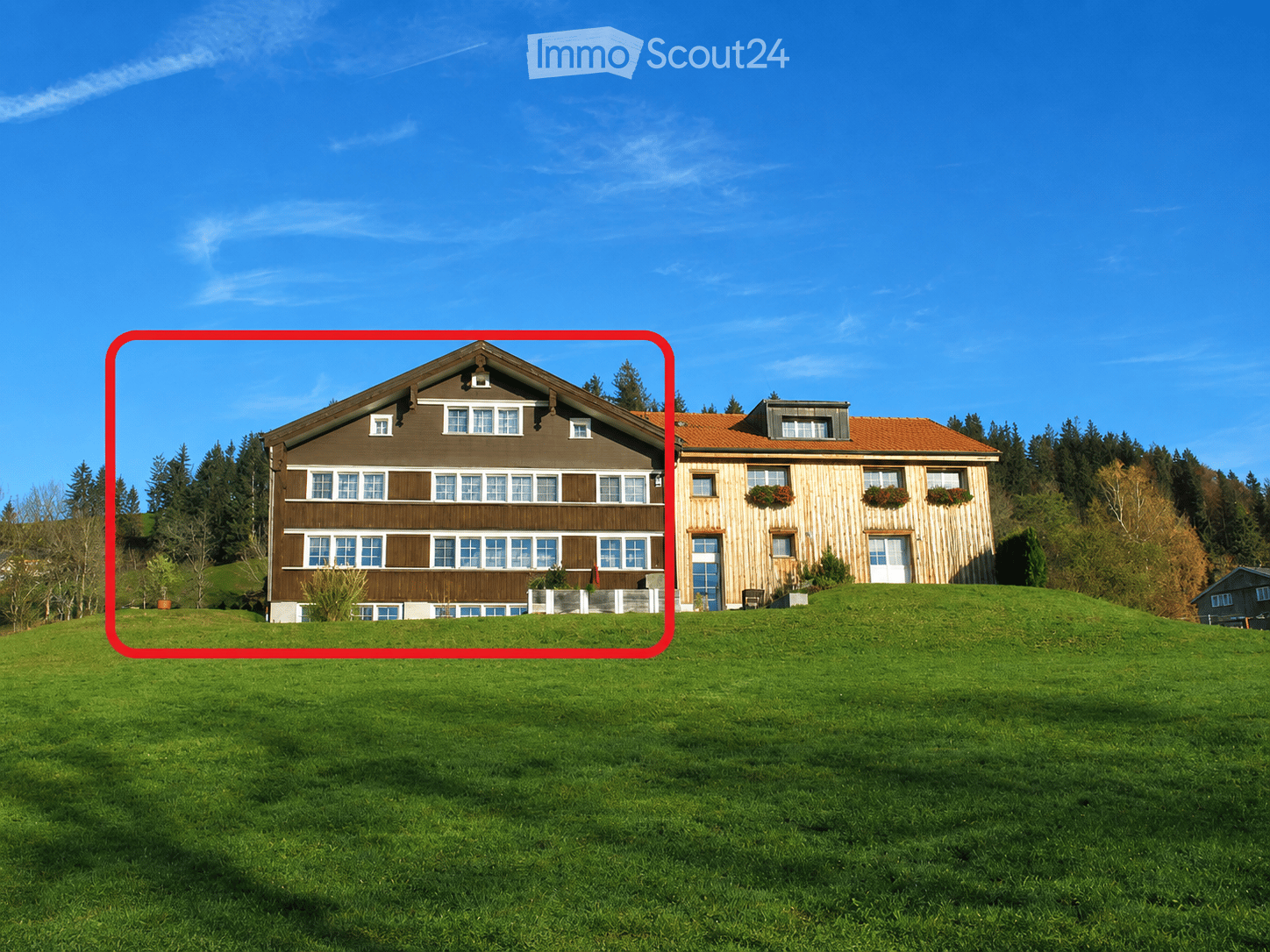 Two-story house with brown and wooden exterior, multiple windows, and a sloped roof, surrounded by green lawn and trees.
