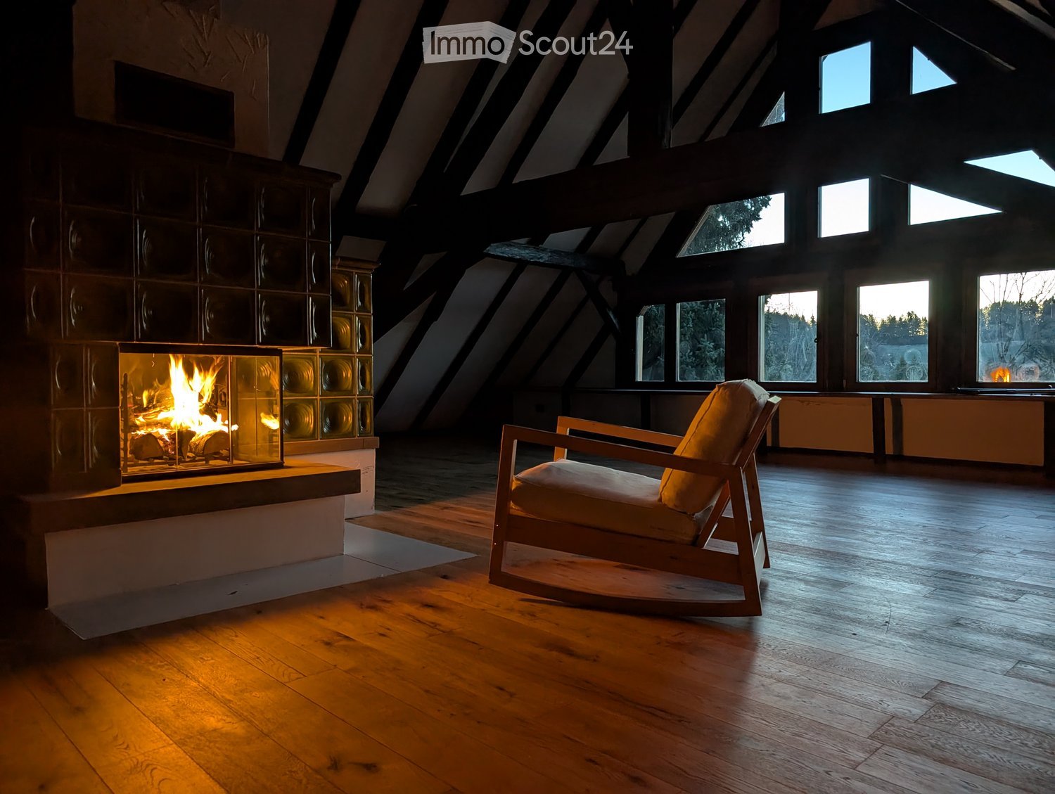Living room with exposed wooden beams, large windows, a modern fireplace, and a single wooden chair.