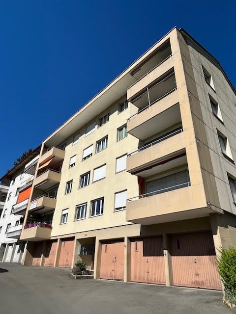 Multi-story residential building with balconies and multiple garage doors.