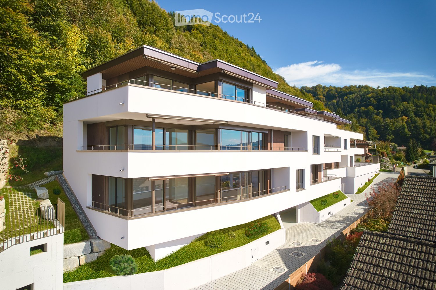 Modern two-story house with white exterior, large windows, balconies, and a scenic mountain view.