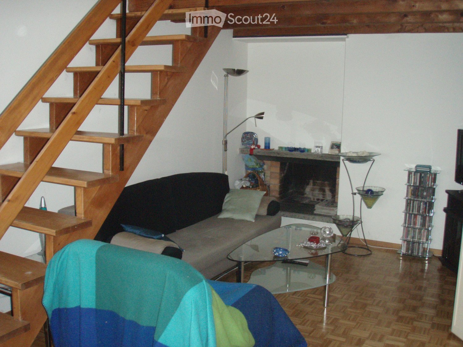 Living room with a wooden staircase, a sofa, a coffee table, a fireplace, and a floor lamp.