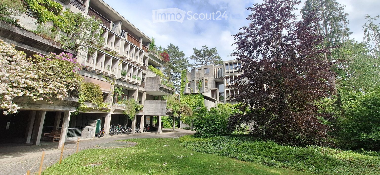 Building. Modern multi-story building with balconies, greenery, and bicycles parked in front.