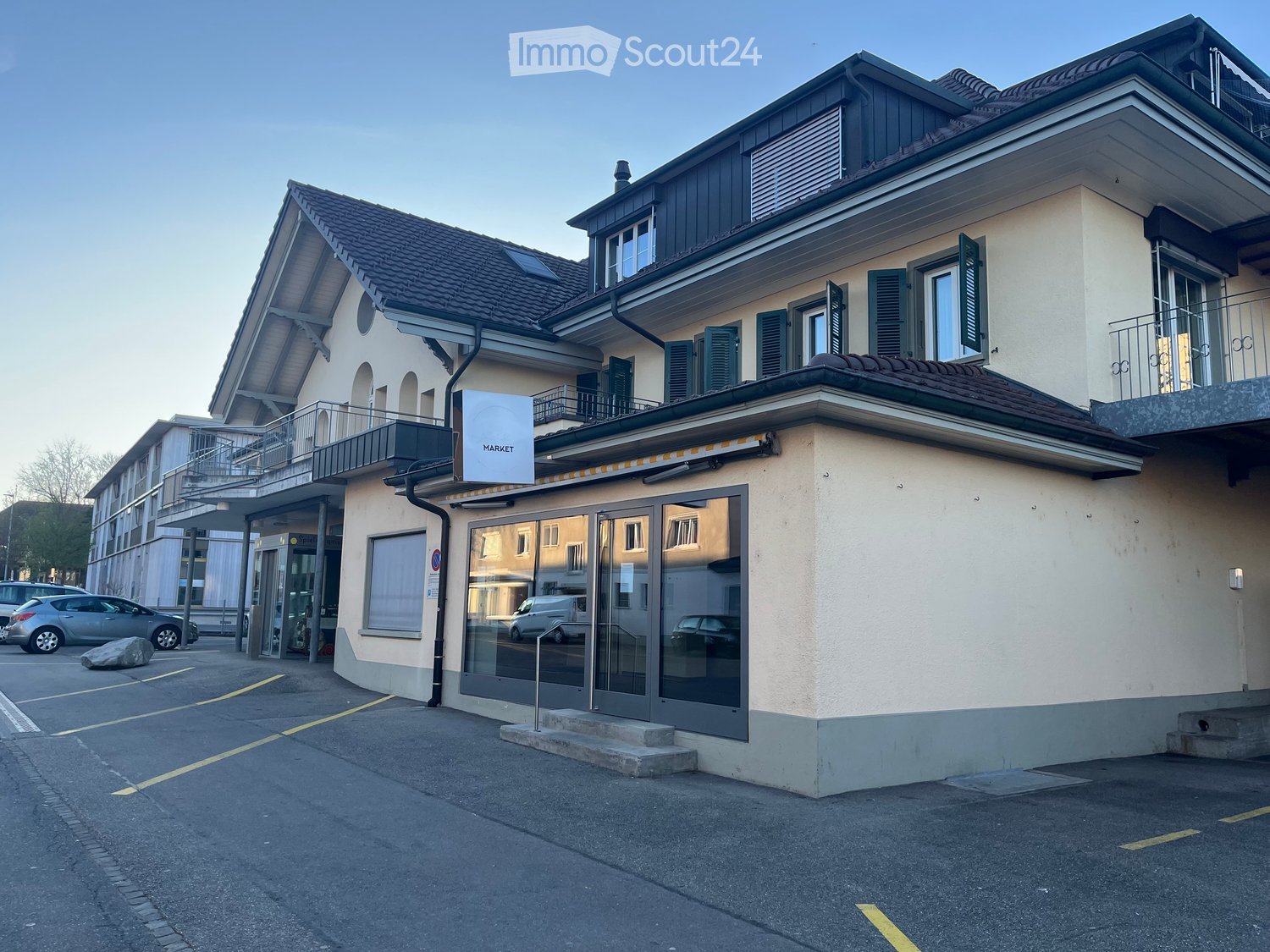 2 story house, beige walls, black roof, glass doors, balcony, parking lot