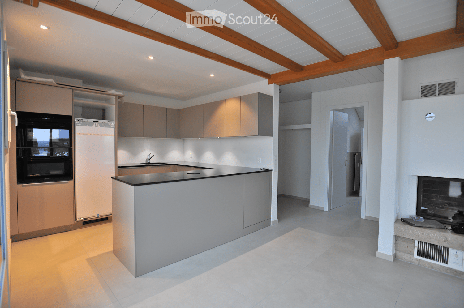Modern kitchen with light wood cabinets, stainless steel appliances, island, and built-in sink.